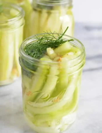 Offenes Glas mit selbst eingelegten Senfgurken, frischem Dill und Senfkörnern nach Omas DDR-Rezept wie früher.