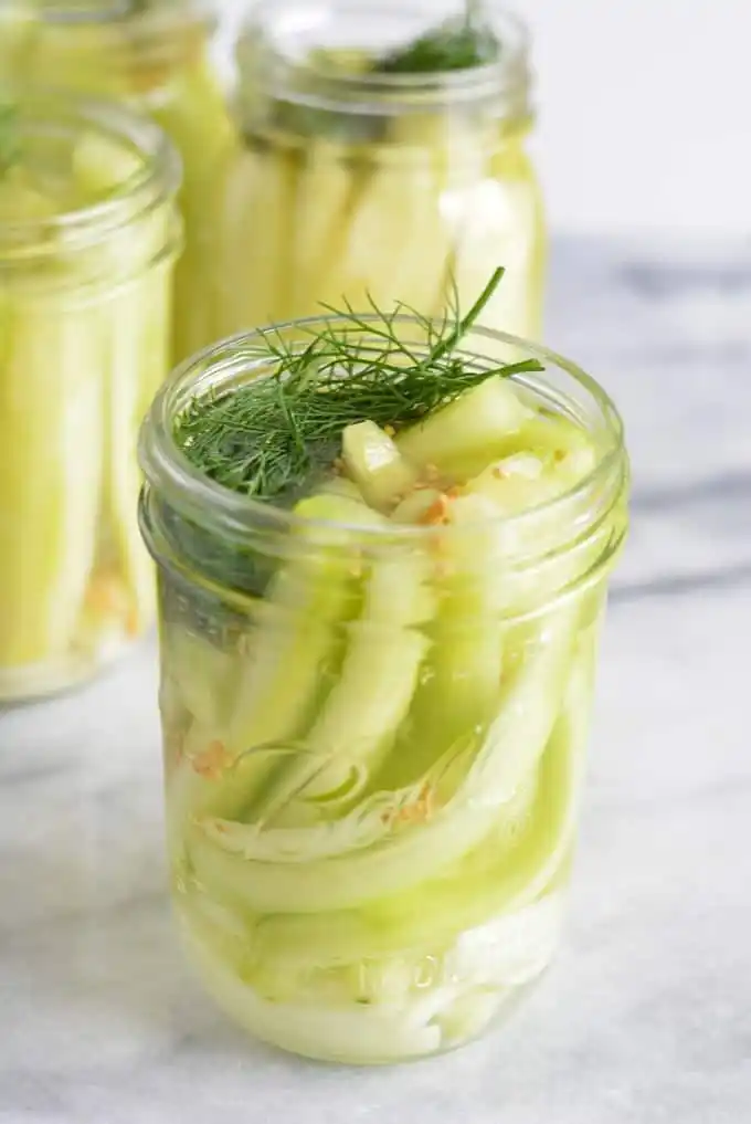 Offenes Glas mit selbst eingelegten Senfgurken, frischem Dill und Senfkörnern nach Omas DDR-Rezept wie früher.