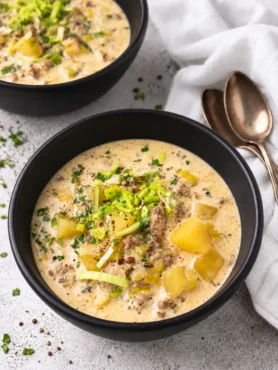 Käse-Lauch-Suppe mit Schmelzkäse, Hackfleisch und Kartoffeln in schwarzen Schüsseln