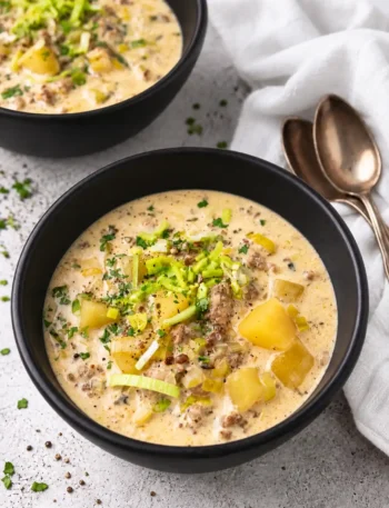 Käse-Lauch-Suppe mit Schmelzkäse, Hackfleisch und Kartoffeln in schwarzen Schüsseln