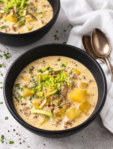 Käse-Lauch-Suppe mit Schmelzkäse, Hackfleisch und Kartoffeln in schwarzen Schüsseln