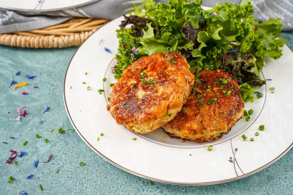 Zwei goldbraun gebratene Tiroler Kaspressknödel mit Bergkäse, Schnittlauch und Blattsalat